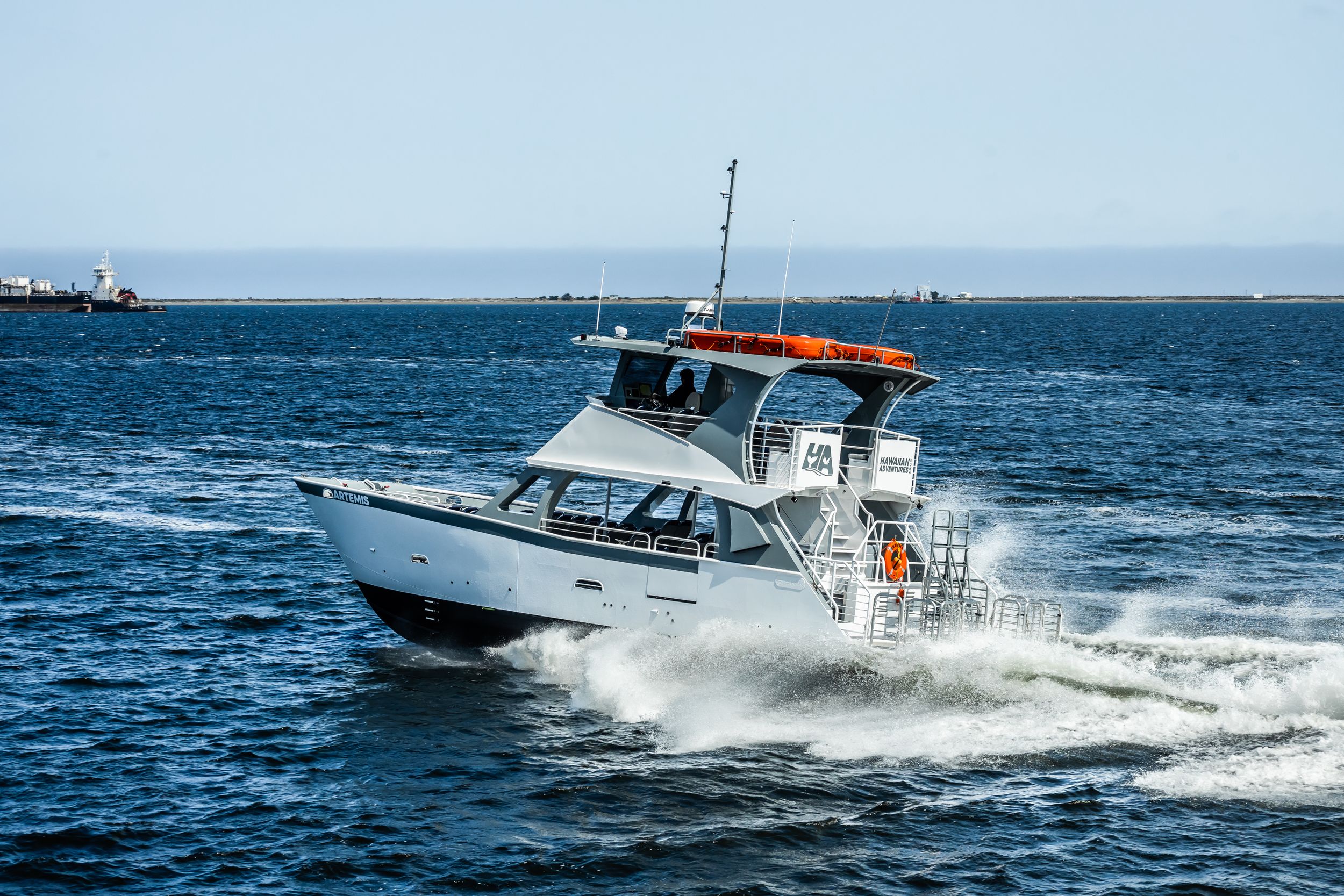 White sport fishing boat speeding through blue ocean waters creating wake spray.
