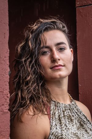 Artistic portrait against terracotta colored wall with dramatic lighting.