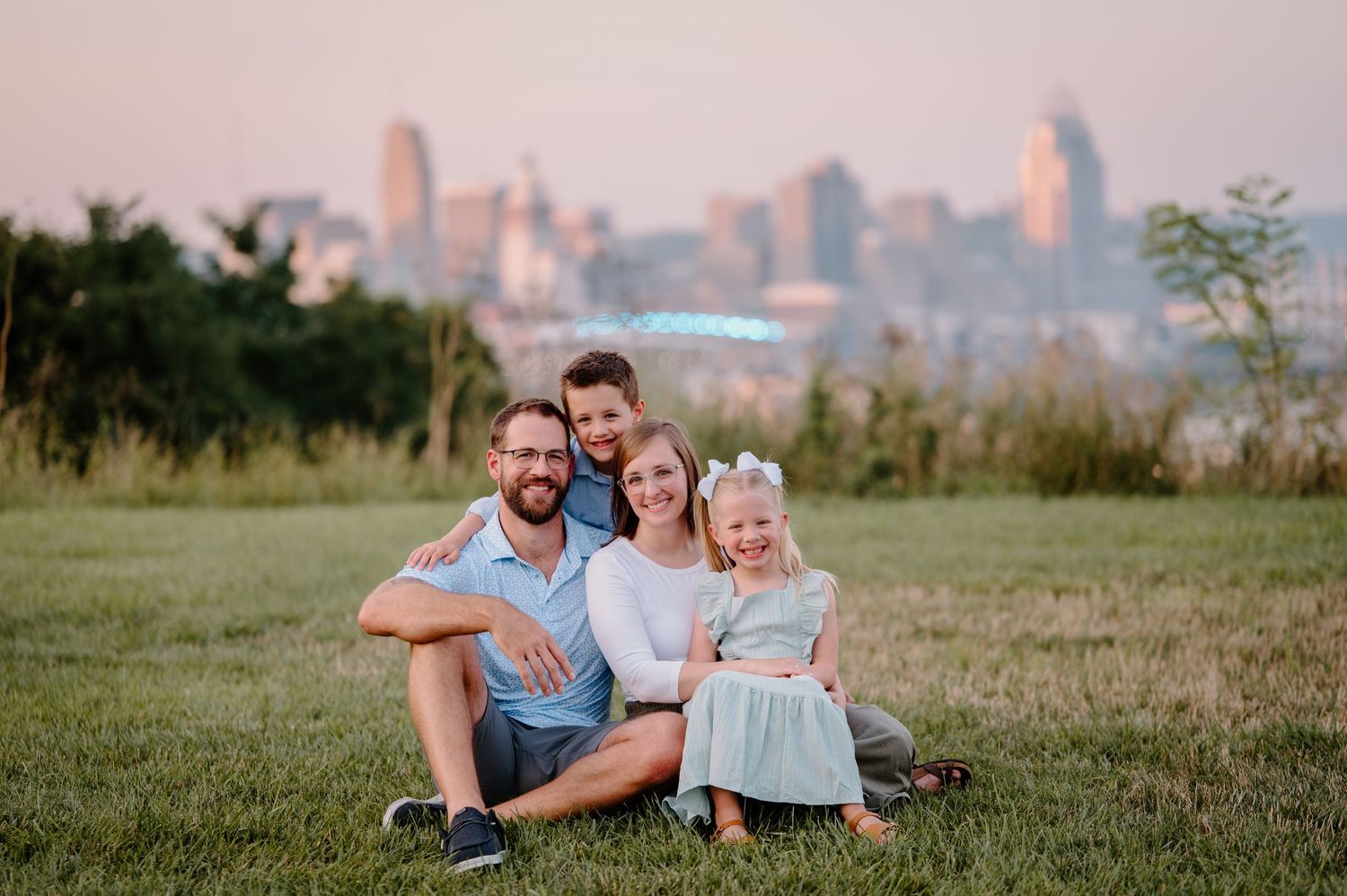 Family portrait of four people sitting together on grass during autumn.