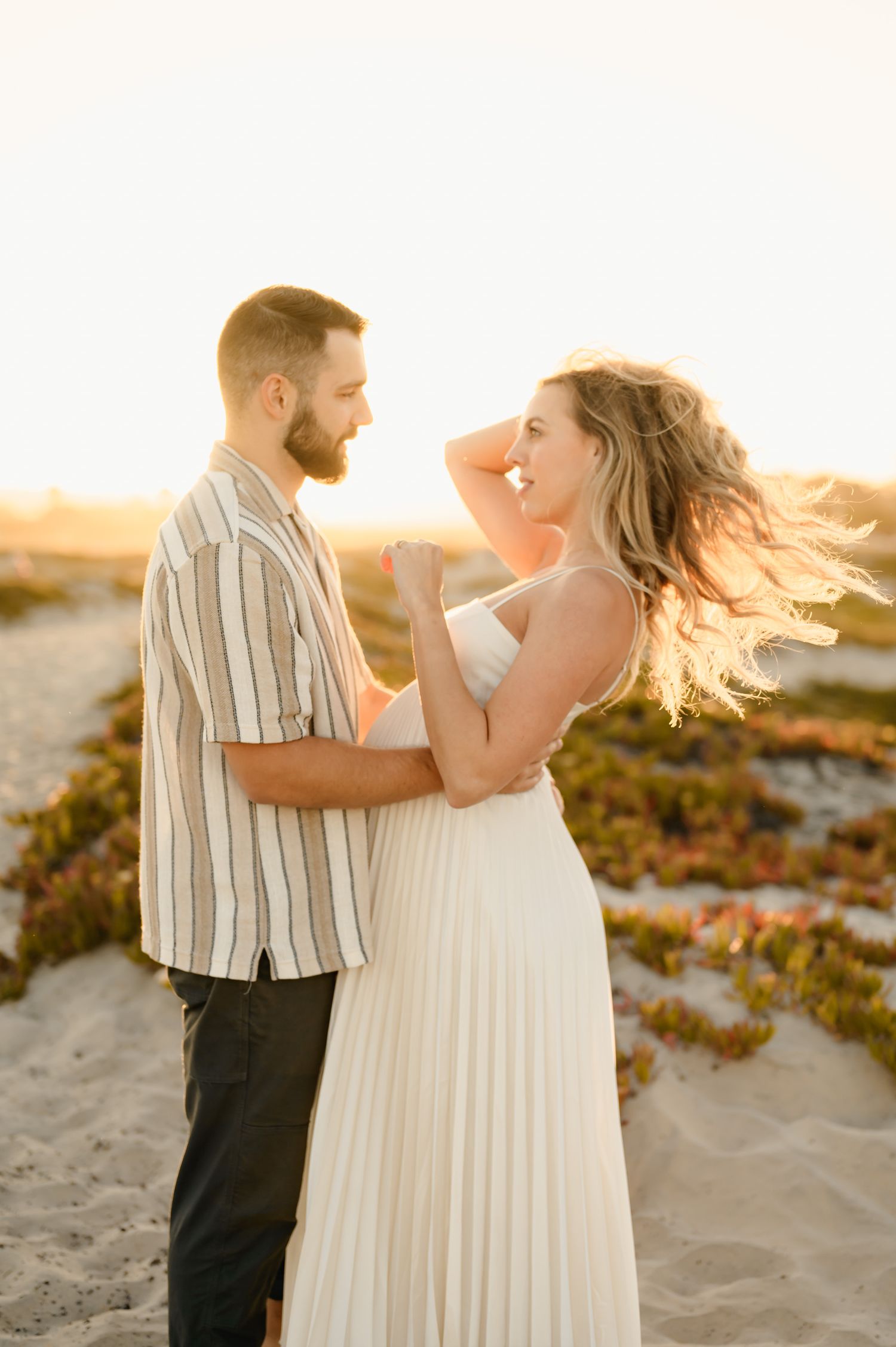 Santa Barbara babymoon maternity photoshoot of couple standing in sunlight on dunes by Ventura maternity photographer