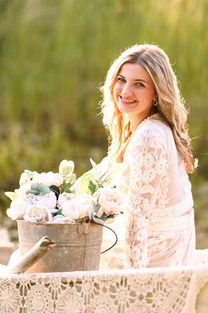 Woman in lace dress poses with vintage decor during outdoor summer photo session.