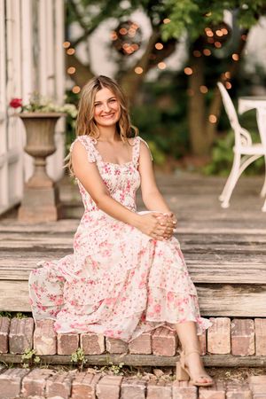 A floral pink dress creates a romantic mood on a rustic brick porch setting.