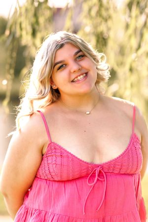 Bright pink camisole top captured in warm natural lighting against soft foliage background.