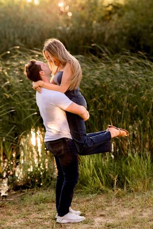 Couple shares tender moments in golden sunset light among tall grasses.