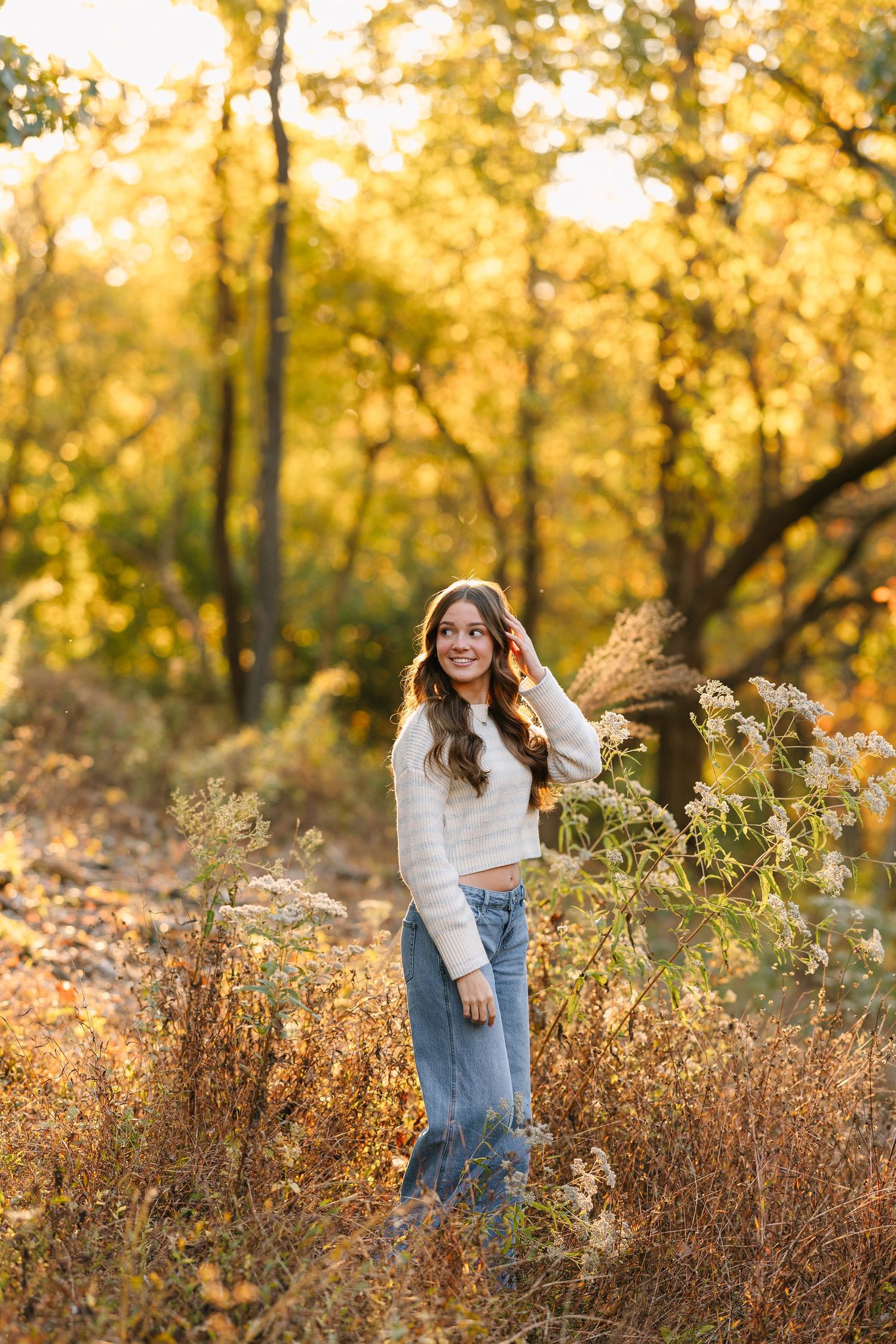 Casual portrait of person sitting against hay bale wearing baseball cap and hoodie in autumn setting.