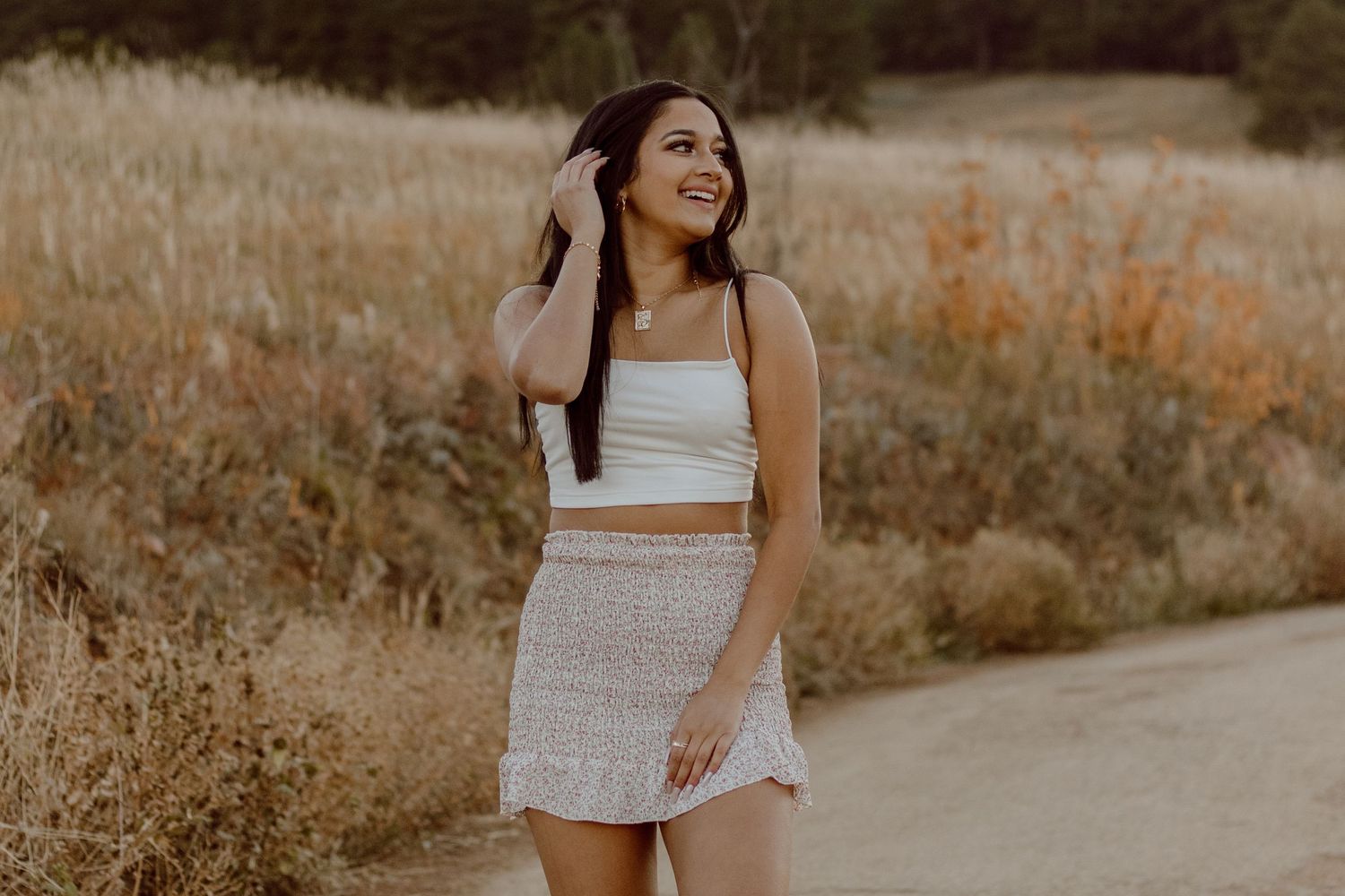 Highschool aged girl facing the camera and looking to the right. Dry grass field behind her