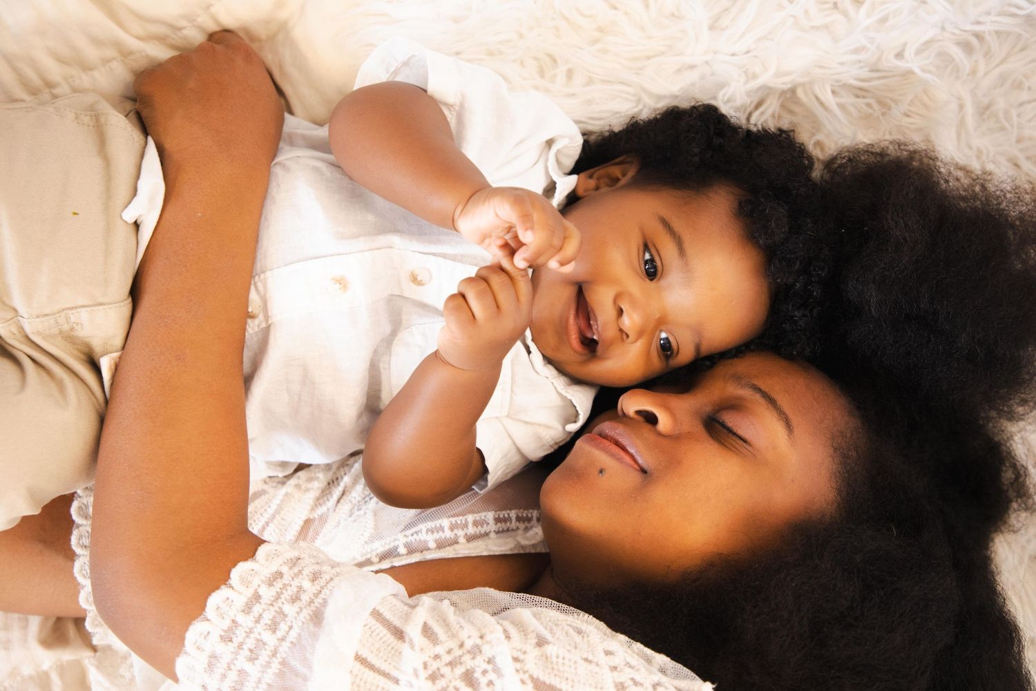 Artistic portrait photography session with white bedding and soft natural lighting.