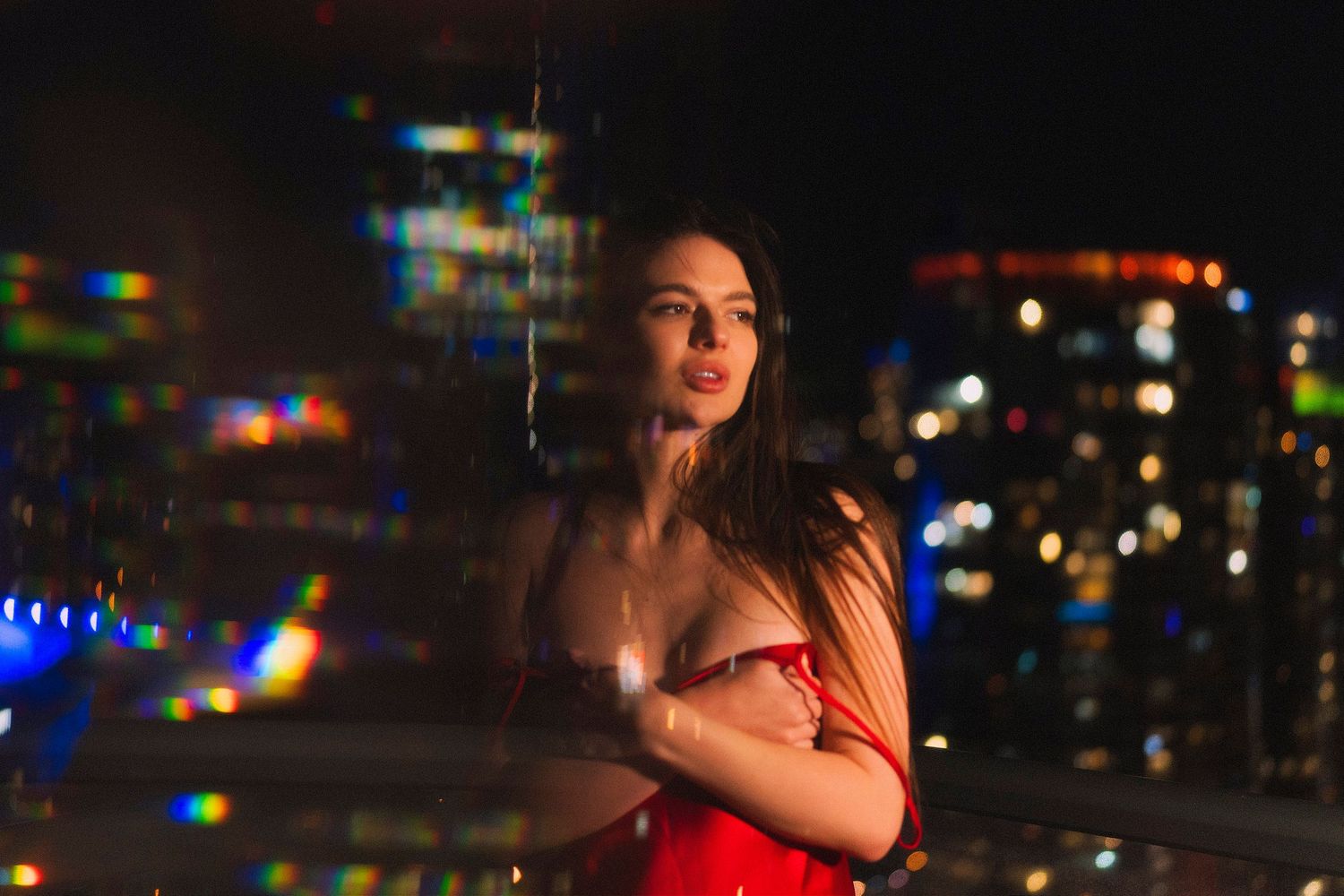 Atmospheric nighttime portrait against an urban skyline with glowing lights.