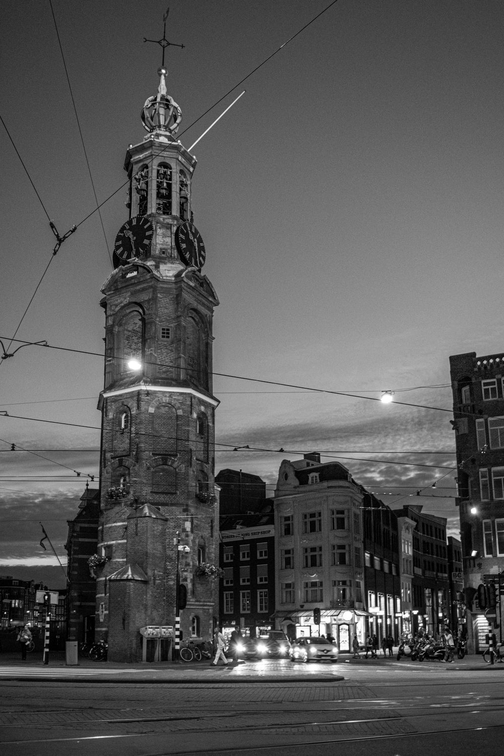 Black and white photo of the Munttoren clock tower in Amsterdam at dusk.