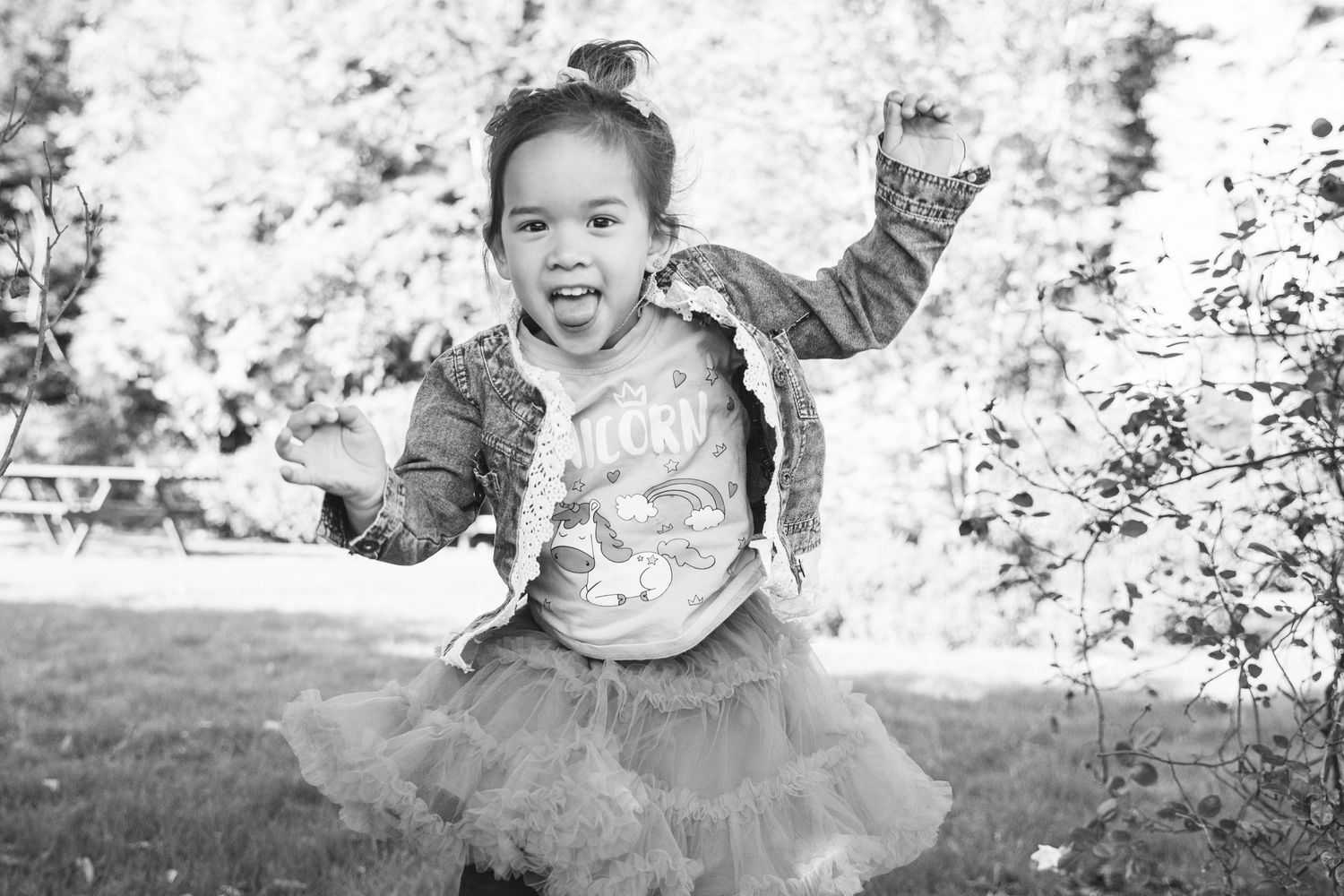 A black and white action shot showing energetic movement in a tulle skirt outdoors.