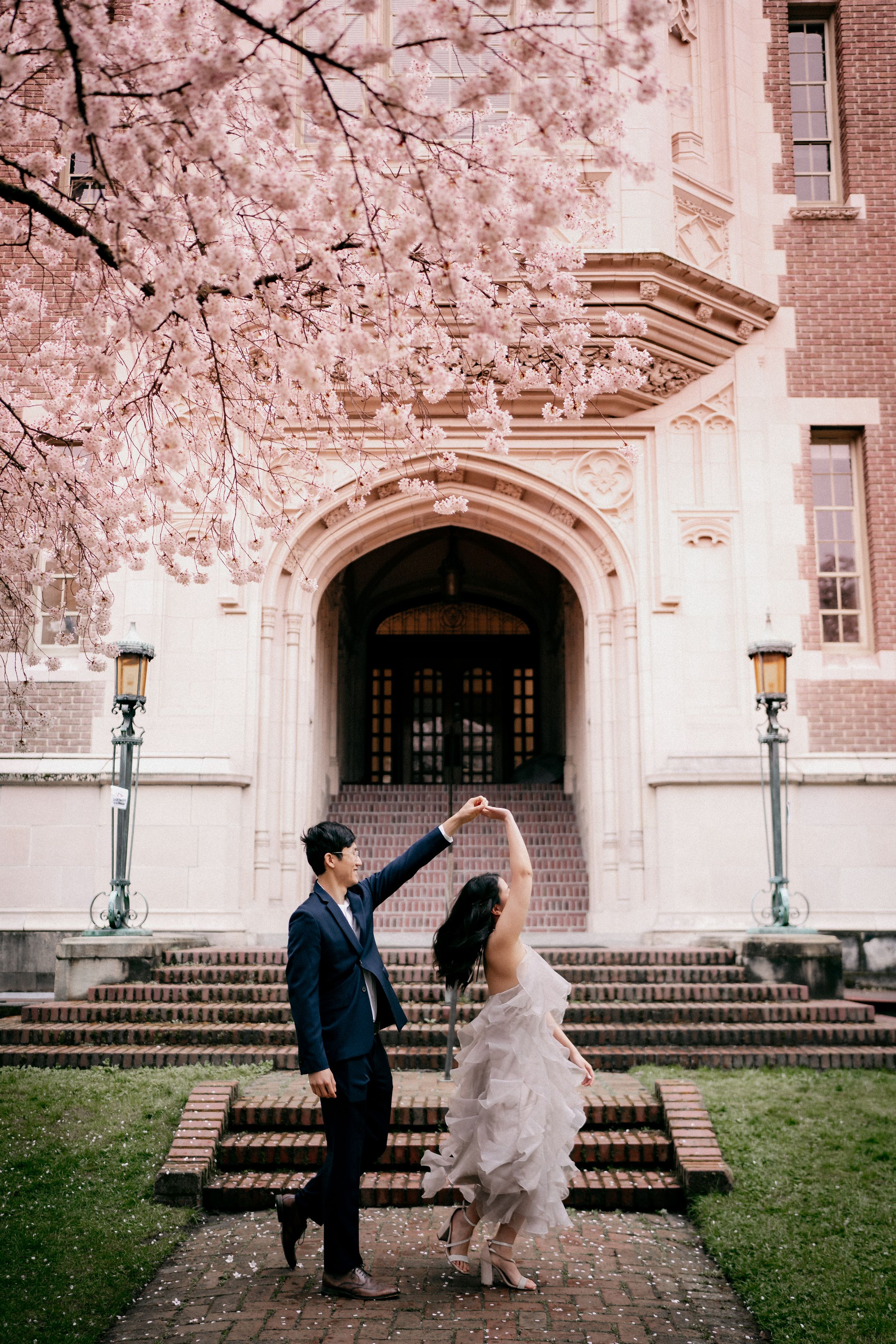 Two people dancing at UW Quad in Seattle beside cherry blossoms