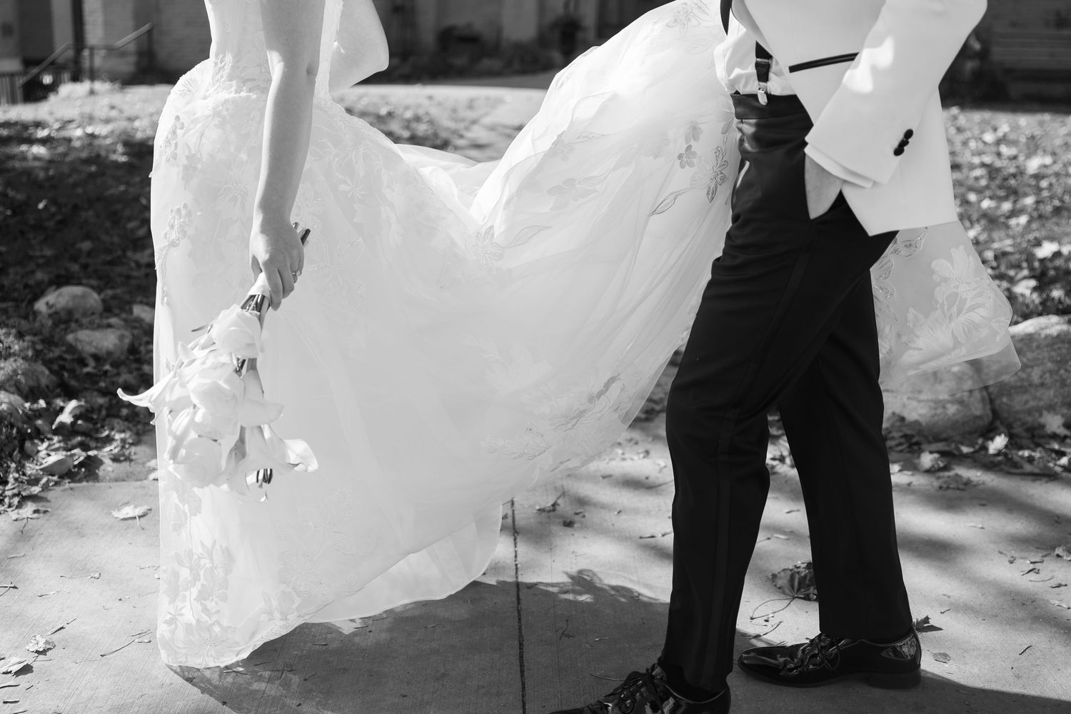 Wedding couple poses under gothic stone archway of historic university building.