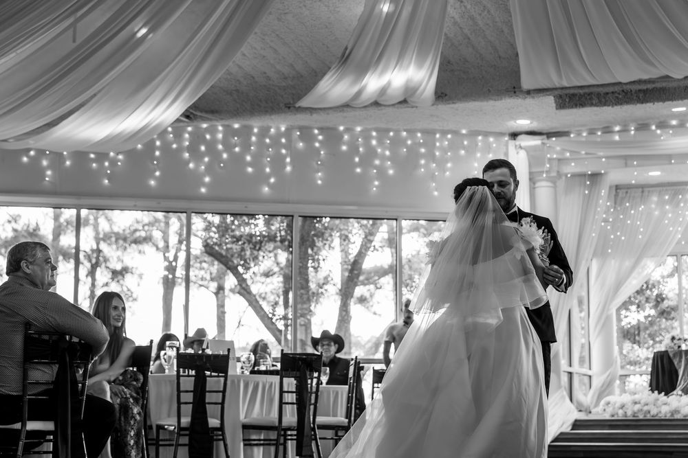 A couple shares their first dance under a romantic tent decorated with twinkling lights at their outdoor wedding reception.