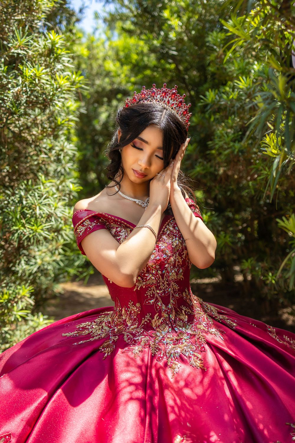 A stunning fuchsia pink quinceañera gown with intricate beaded bodice sparkles in a sunlit garden setting.