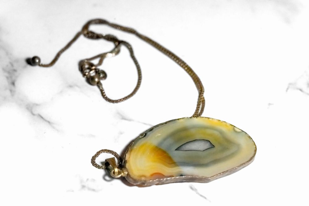 Natural agate slice pendant on bronze chain necklace featuring yellow and grey tones.