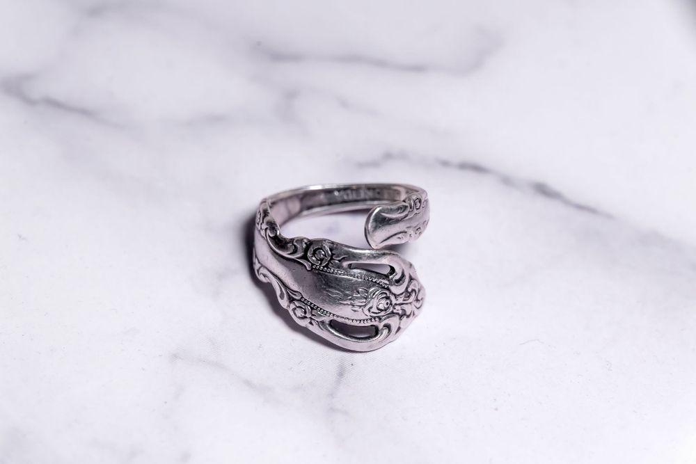 Handcrafted silver spoon ring with intricate Victorian scroll design on white marble.