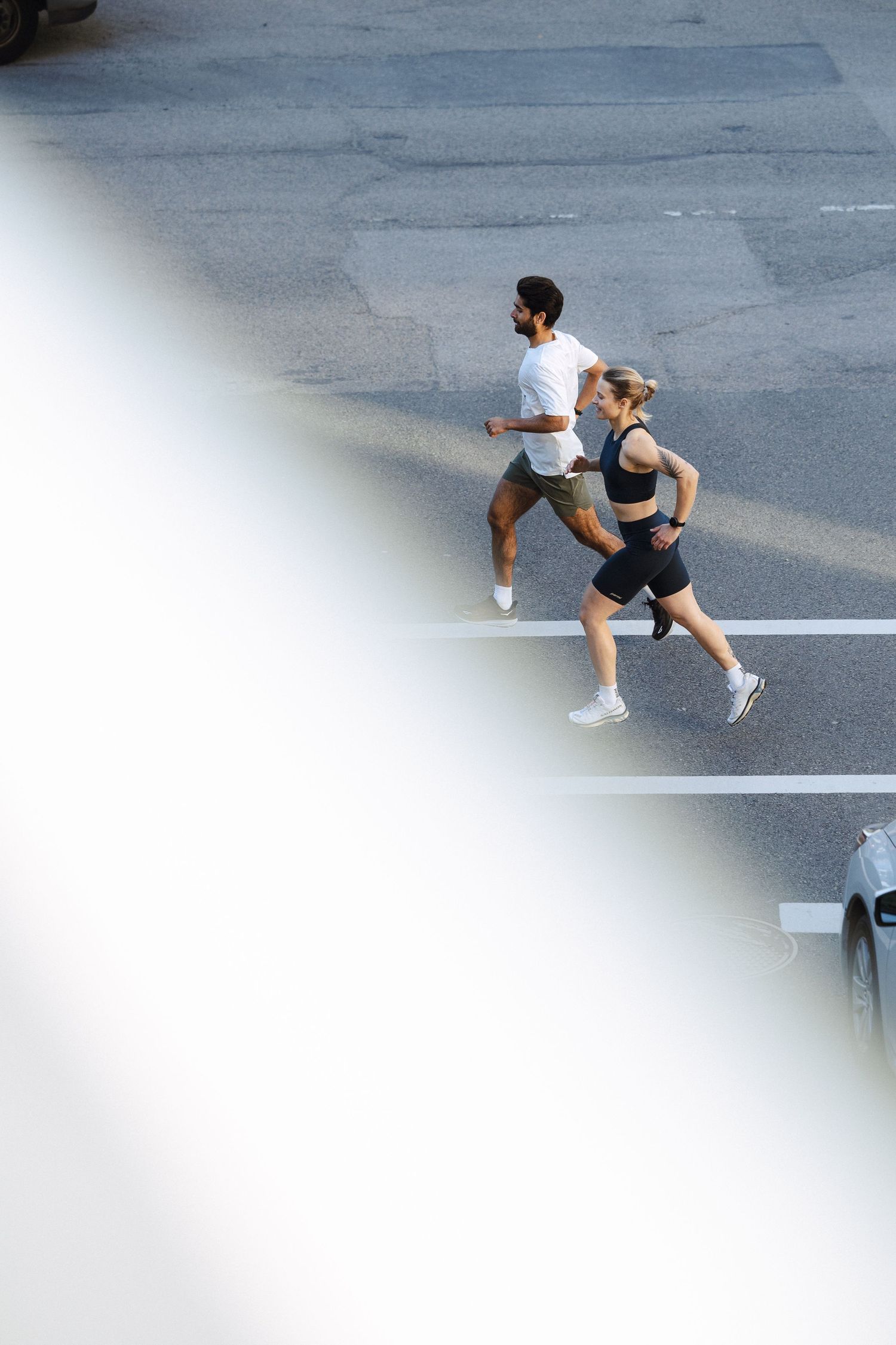 Aerial view of two people jogging together on city street.