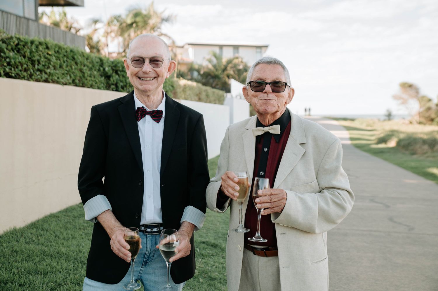 Two guests in formal attire share drinks on an outdoor patio.