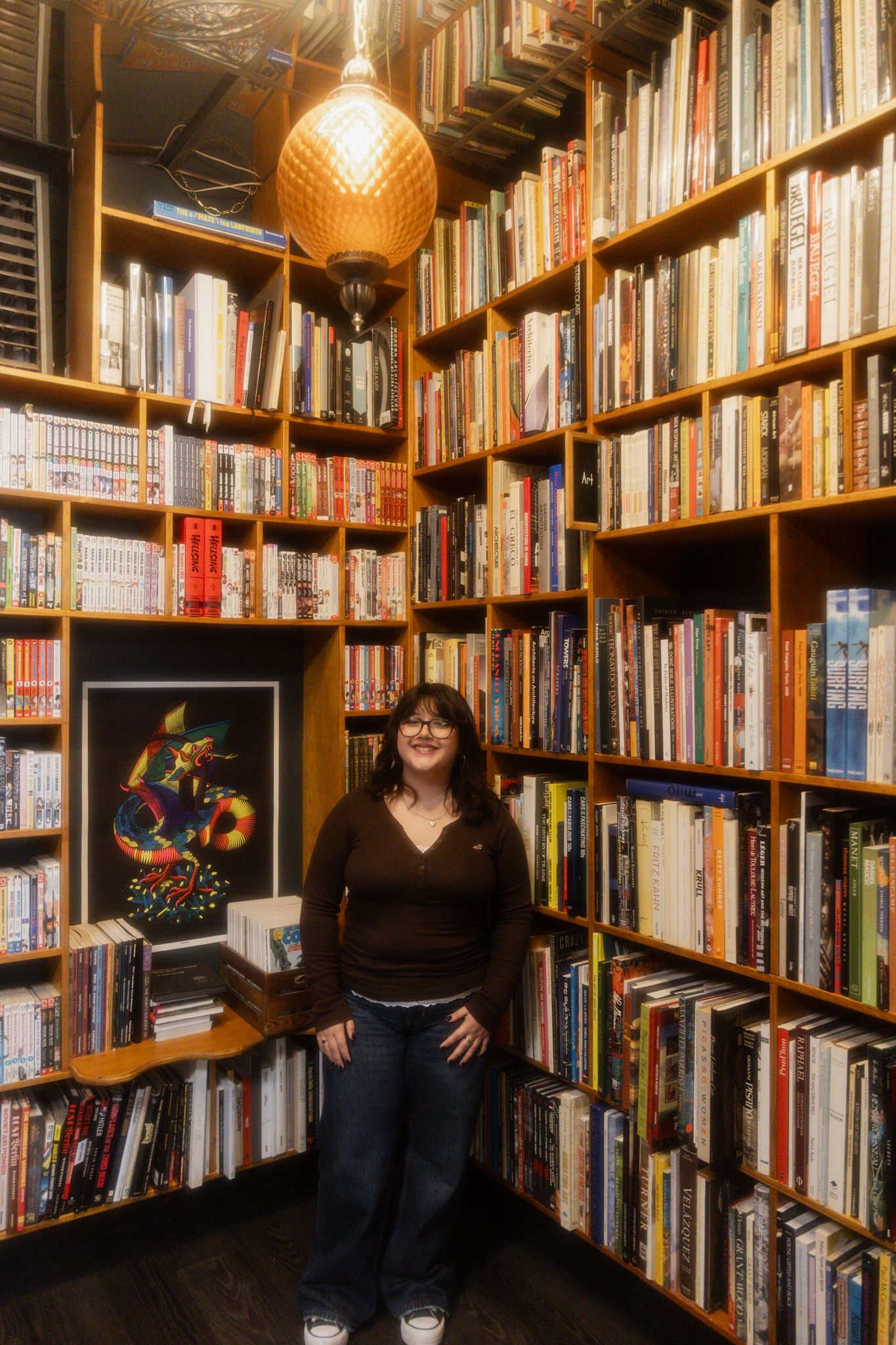 A cozy library interior with wooden bookshelves filled with books and warm lighting from vintage-style pendant lamps.