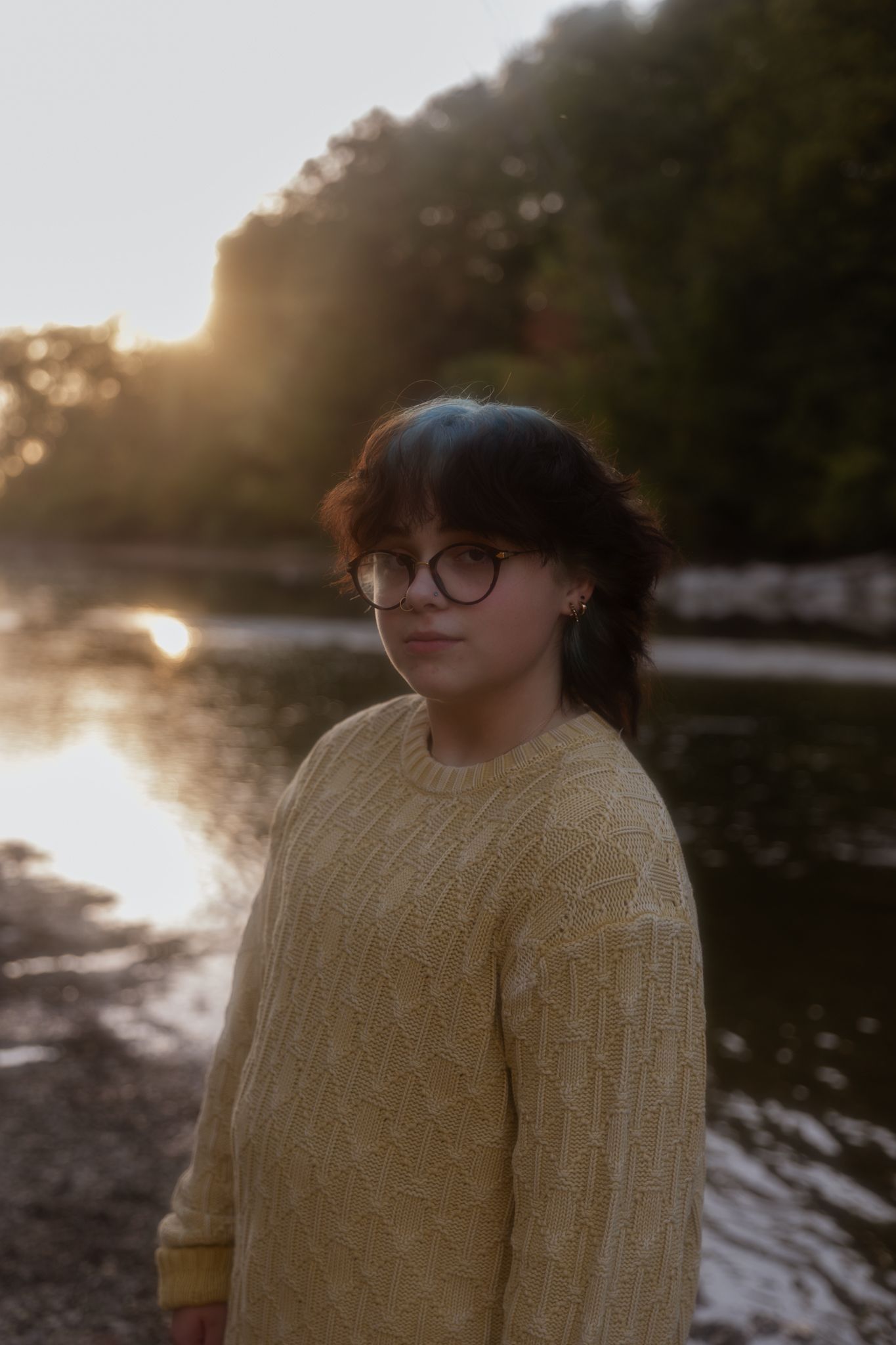 A sunset scene by a lake with golden light filtering through trees.