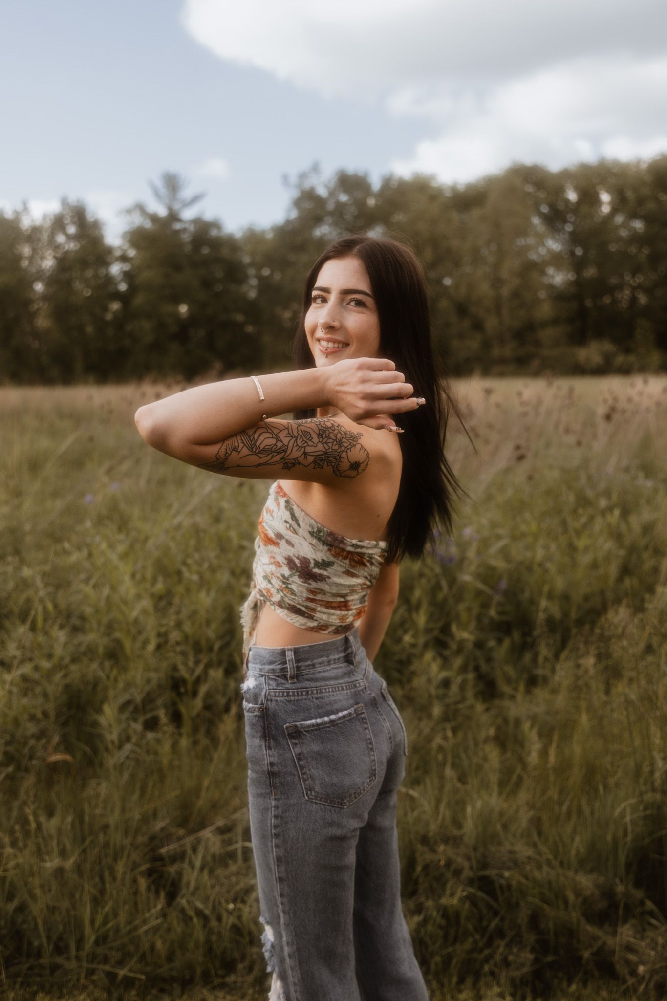 Artistic portrait series in a natural meadow setting with casual denim attire.