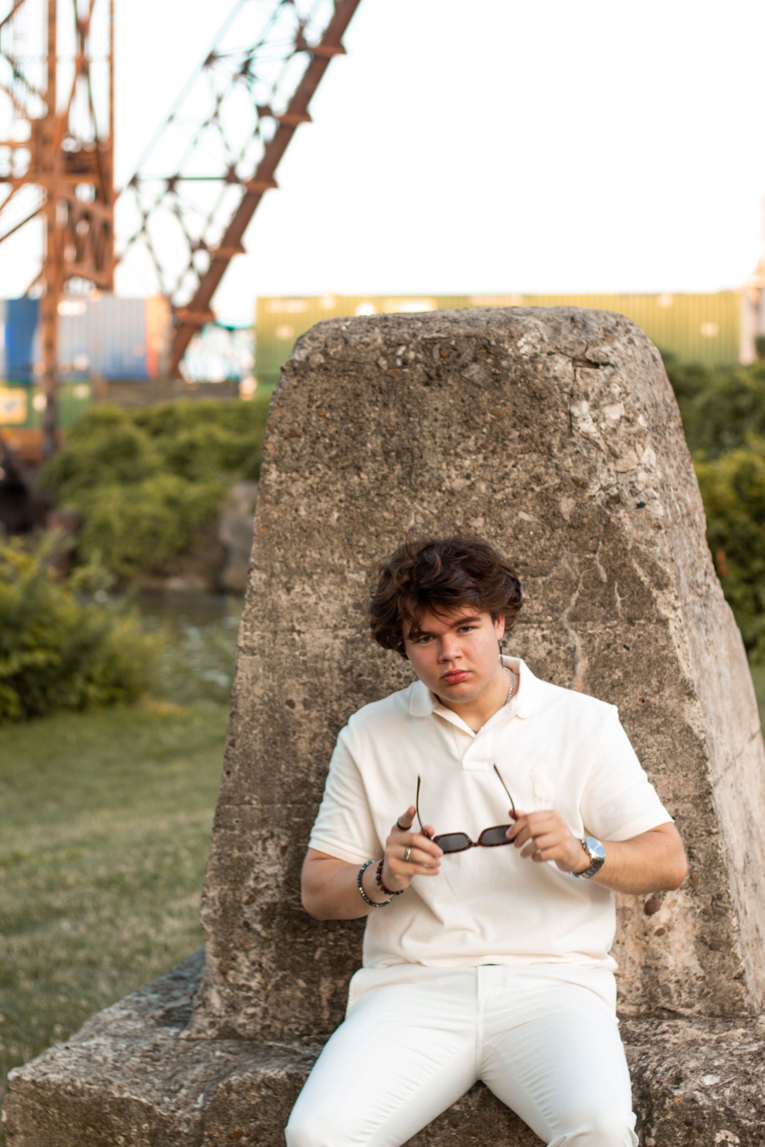 Person in white outfit sitting on concrete structure outdoors during golden hour.