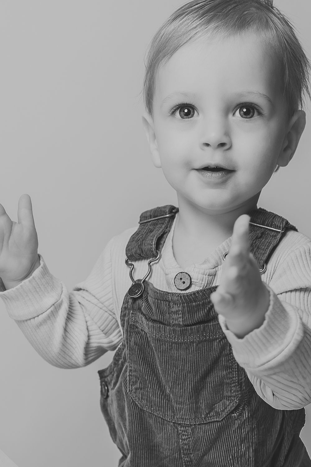 A series of five candid photos showing a small child in corduroy overalls and white shirt making playful expressions.