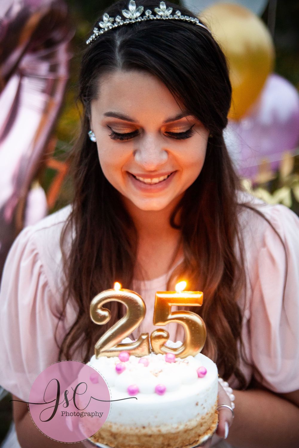 Birthday celebration with lit candles on cake and sparkly tiara decoration.