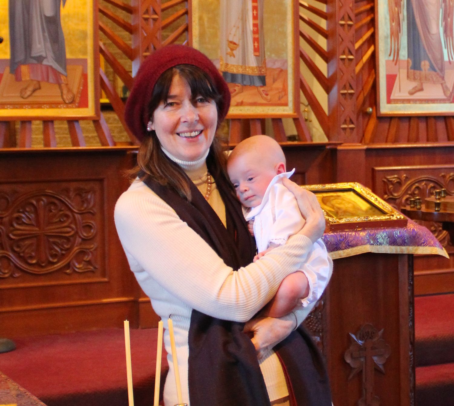A baby in white clothing during a traditional baptism ceremony.