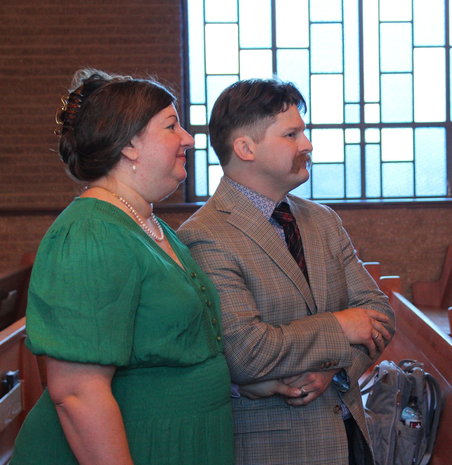 Congregation members standing in church pew during religious service.