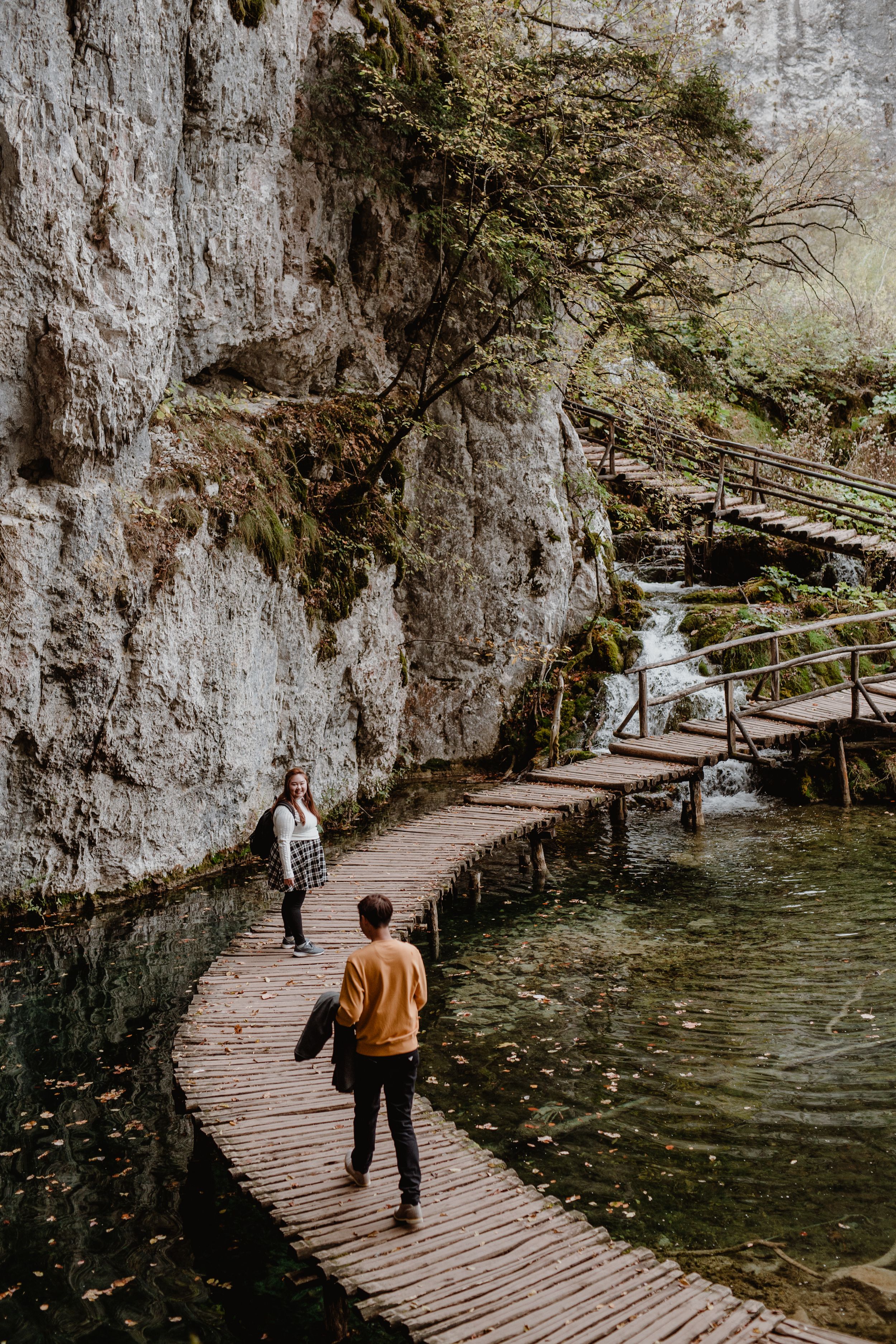 Couple exploring Plitvice National Park during a vacation photoshoot, with the stunning natural scenery.