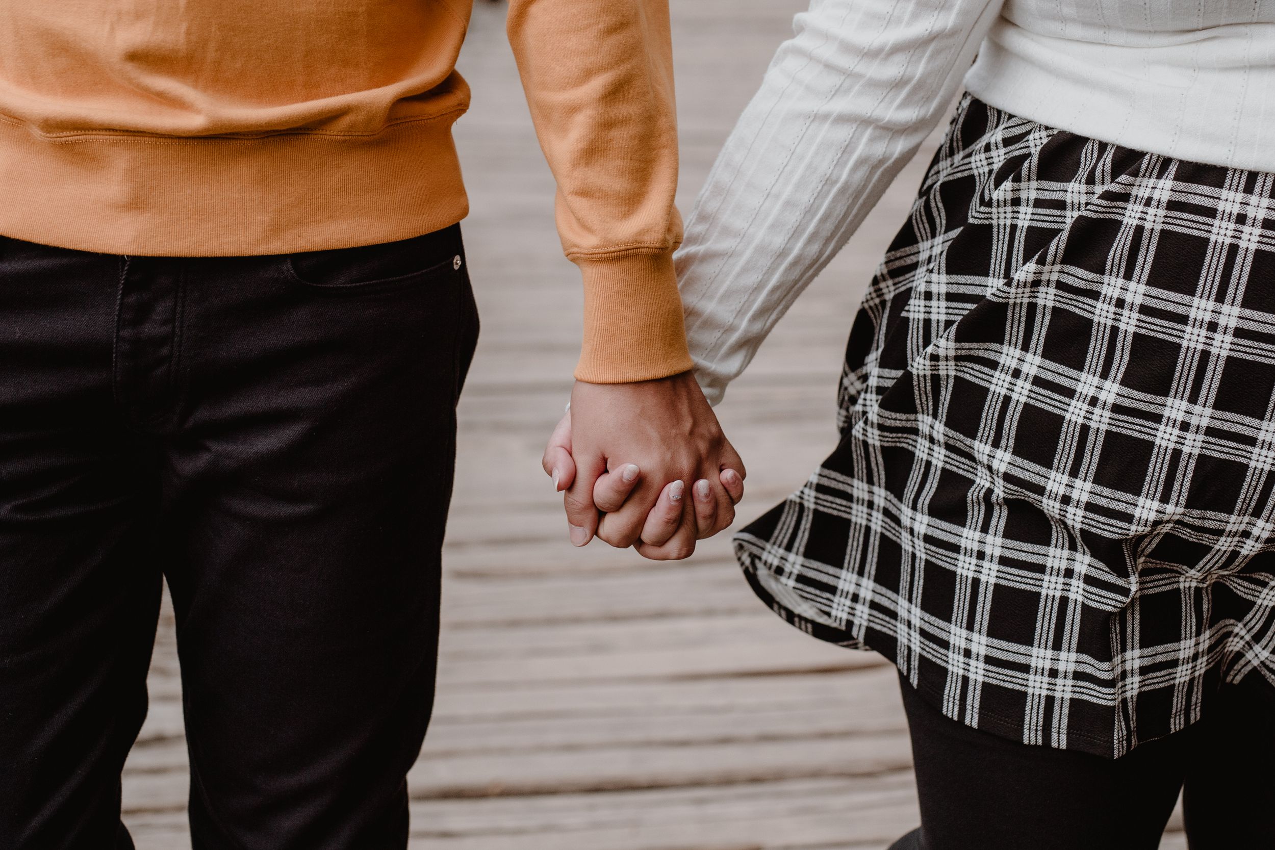 Close-up of a couple’s hands intertwined as they walk through the scenery of Plitvice National Park.