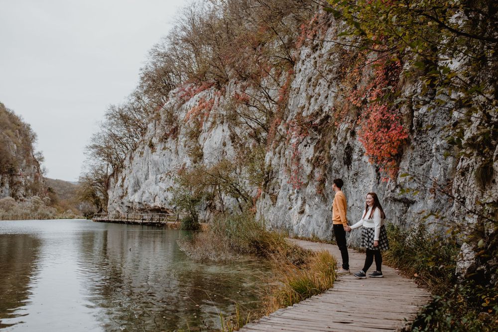Wide shot of a couple exploring the scenic trails of Plitvice National Park, surrounded by the natural beauty.