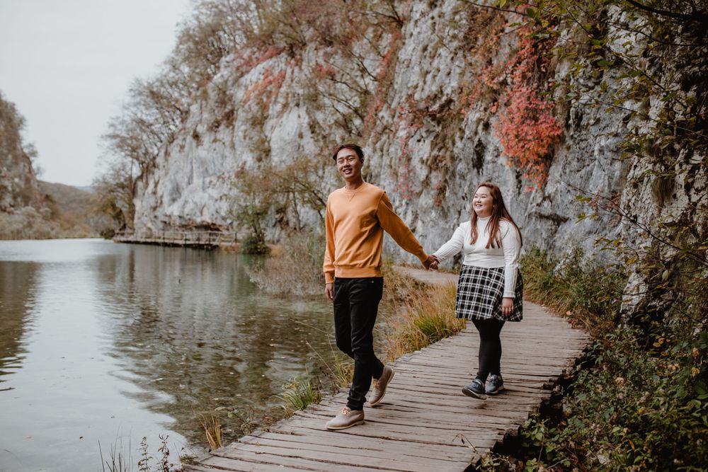 Wide shot of a couple exploring Plitvice National Park, surrounded by its stunning natural landscape.