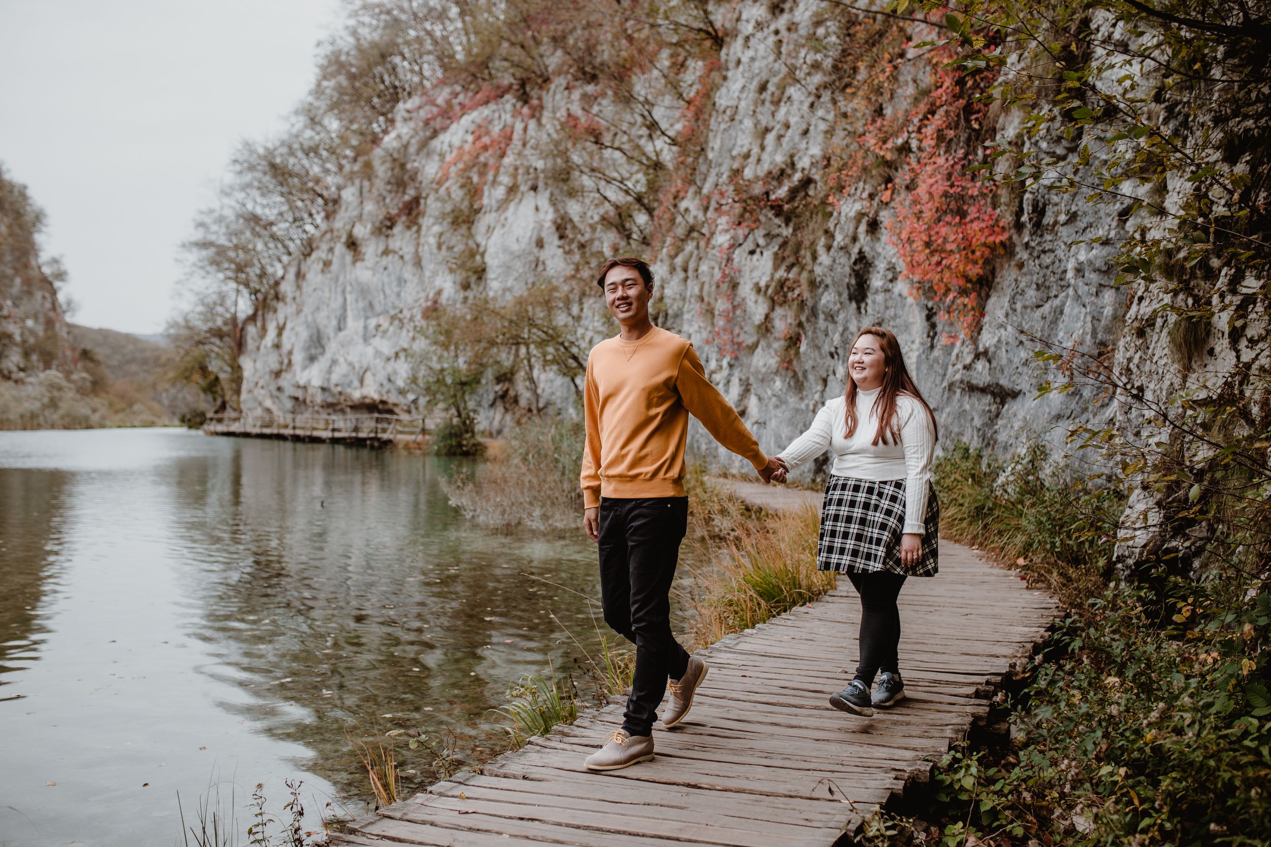 Wide shot of a couple exploring Plitvice National Park, surrounded by its stunning natural landscape.