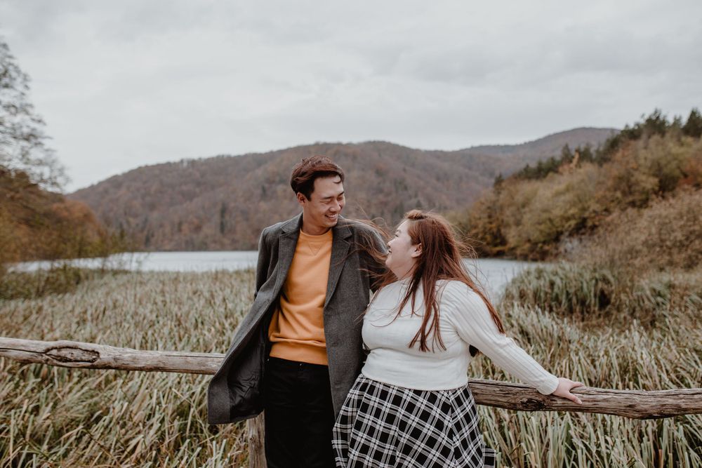Couple standing and looking at each other,smiling and laughing during their vacation photoshoot at Plitvice in Croatia.