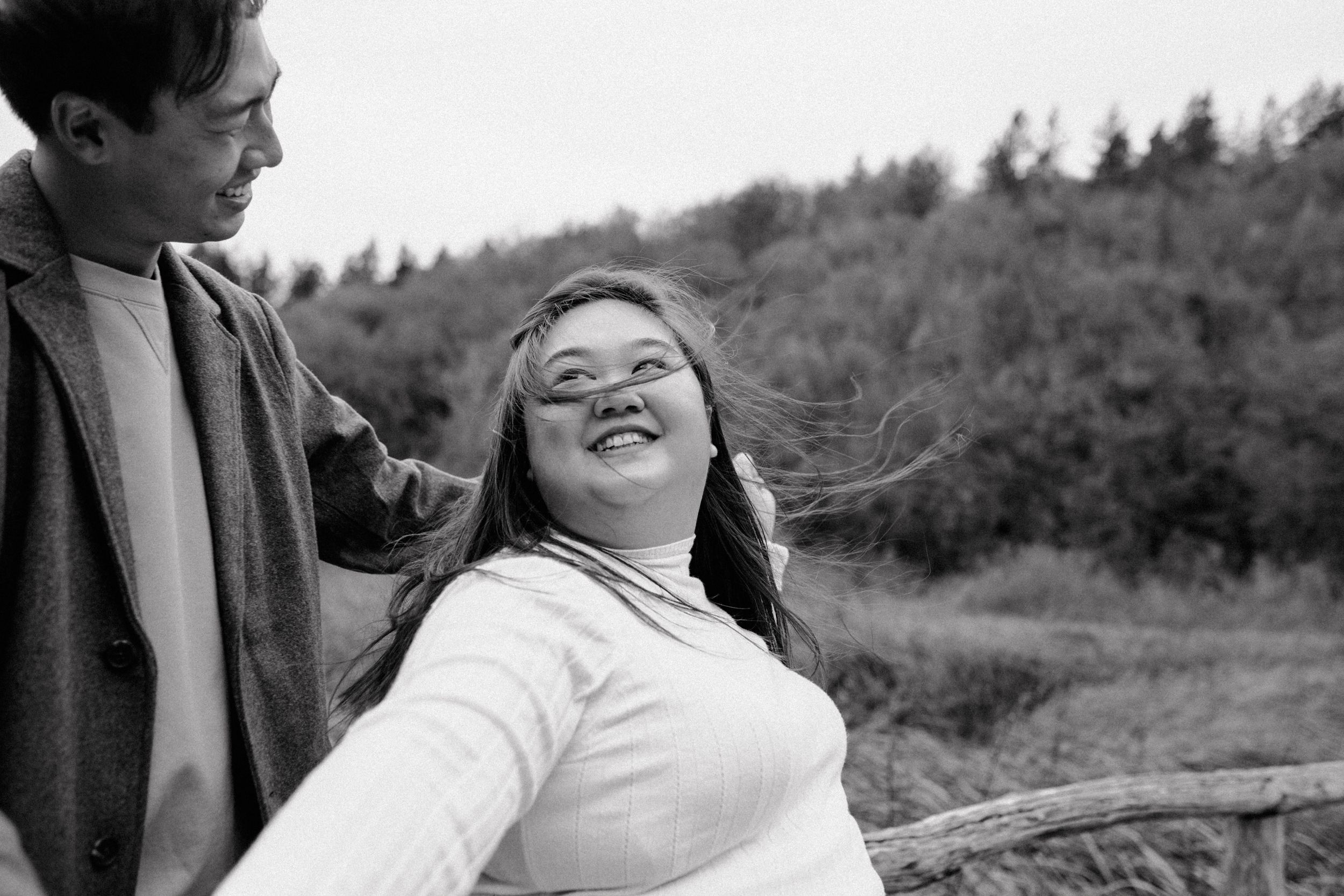 Close-up in black and white of her looking at him and smiling while holding hands during vacation photoshoot.