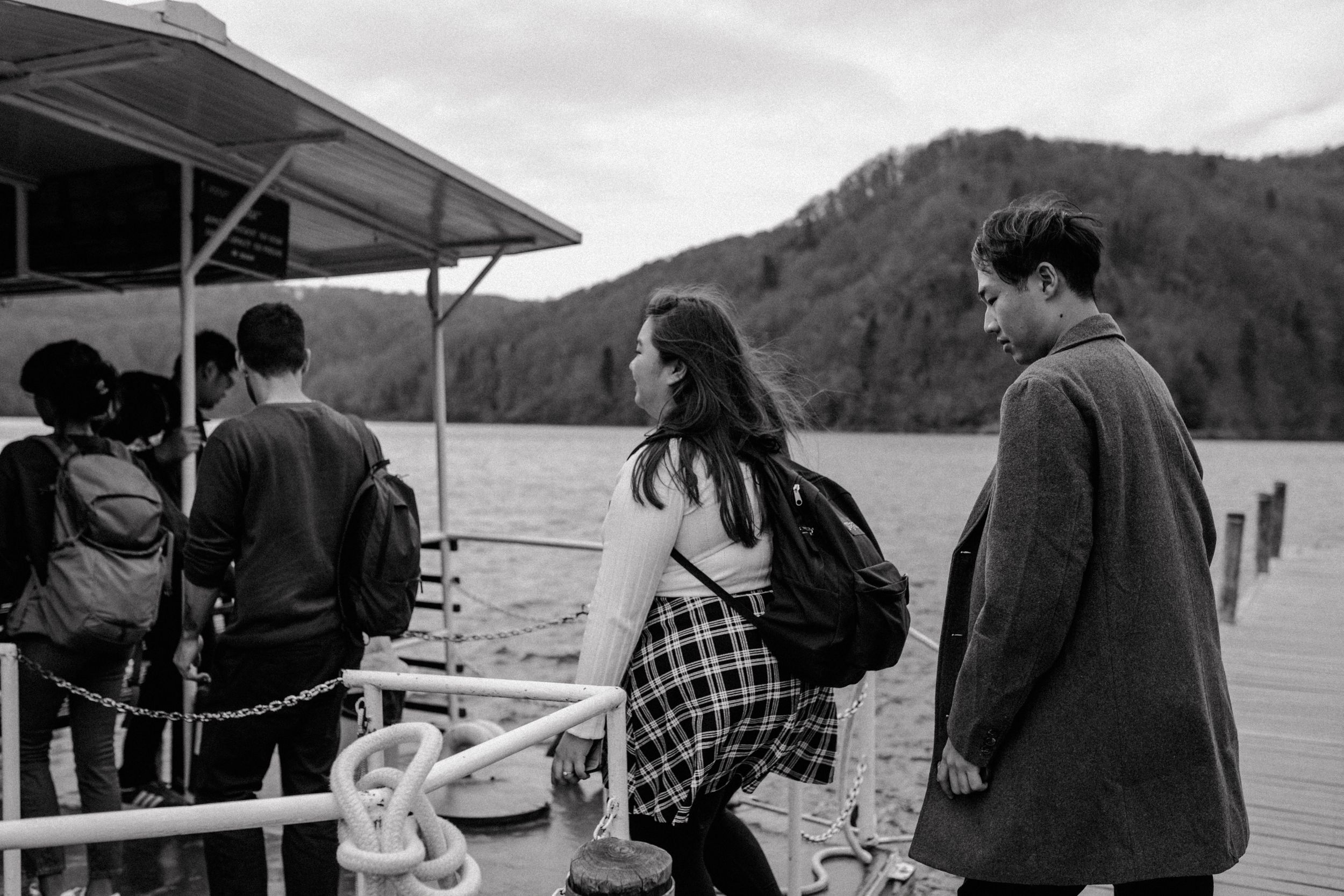 Black and white photo of the couple boarding a boat at Plitvice National Park, capturing a candid moment.