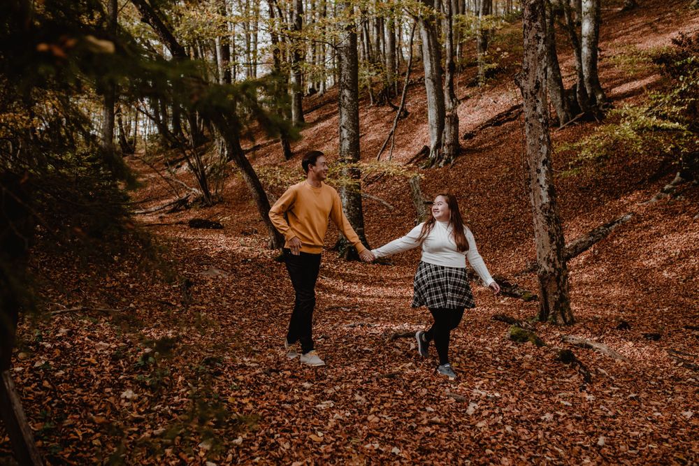 photo of thCouple holding hands walking through the vibrant autumn forest at Plitvice National Park in Croatia.