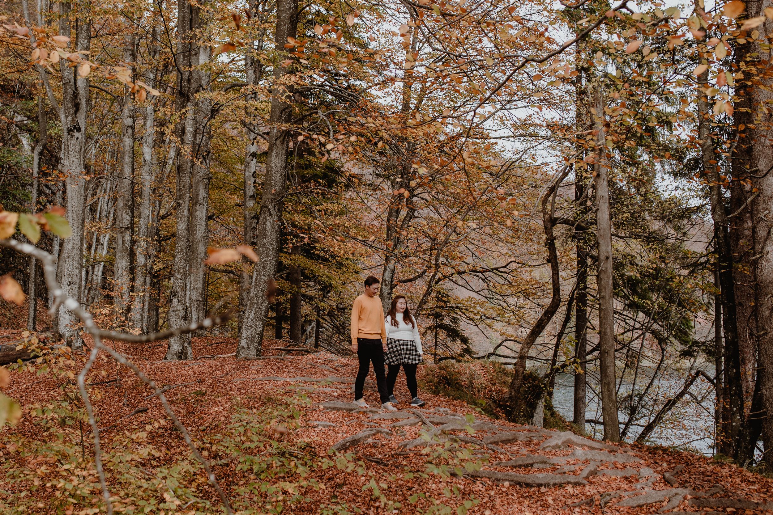 Photo of the couple walking hand in hand through the autumn forest at Plitvice during their vacation shoot.