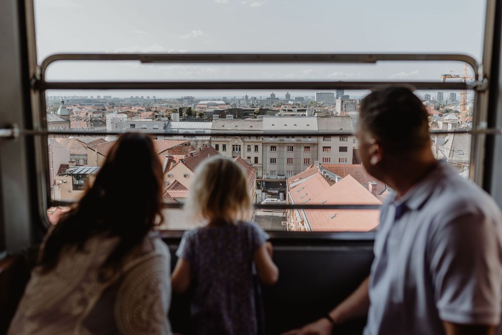 Parents and child sharing a fun moment on the Zagreb funicular, capturing the excitement during vacation photoshoot.