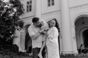 Parents holding their daughter and tickling her, all smiling and sharing a joyful moment during their family vacation.