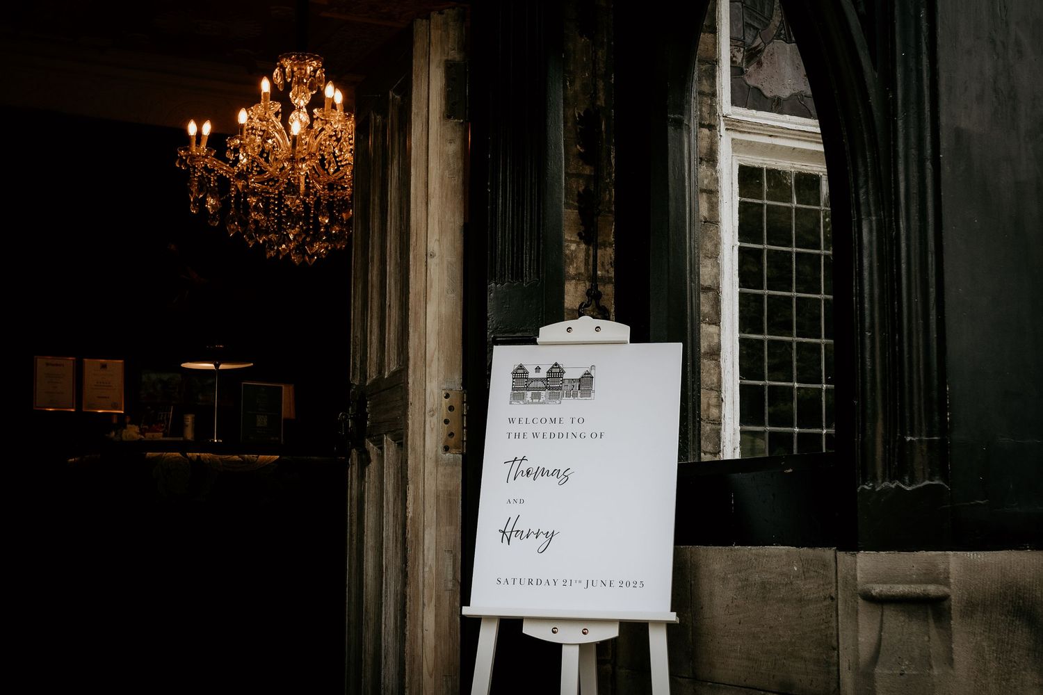 An elegant chandelier hangs in a dimly lit room with vintage-style windows and ornate architectural details.