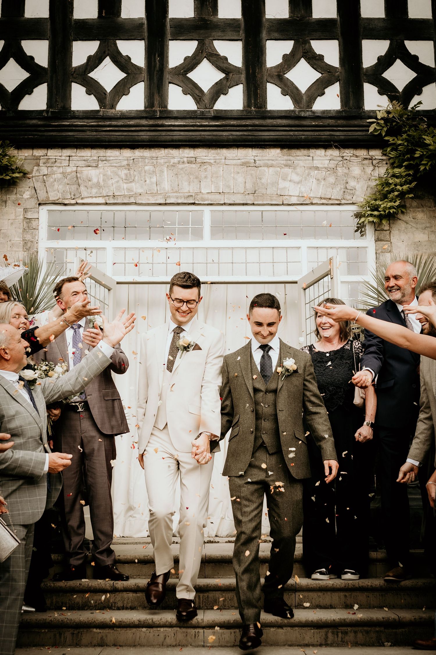 A group wearing formal attire poses playfully against a white ornate fence backdrop.