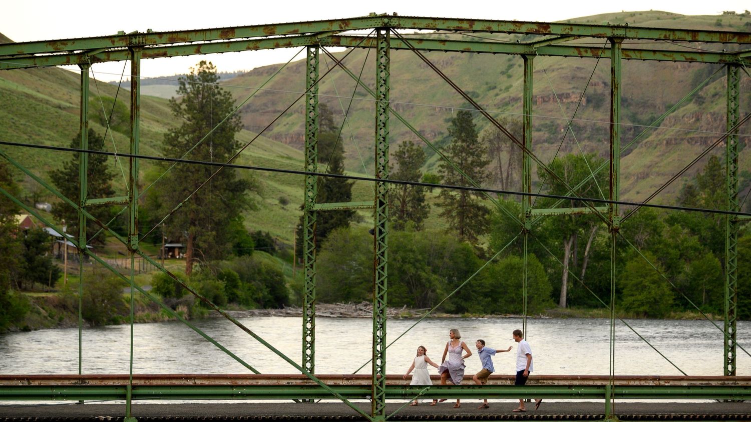People walking across elevated railroad bridge with scenic mountain valley views. Family Portrait, Troy Oregon