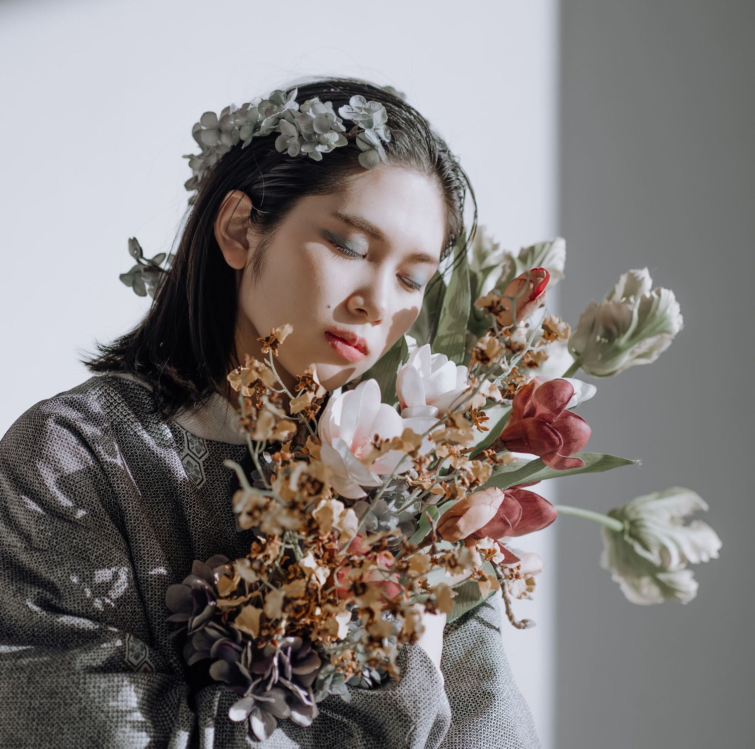 Portrait of an Asian girl with closed eyes holding flowers against her face