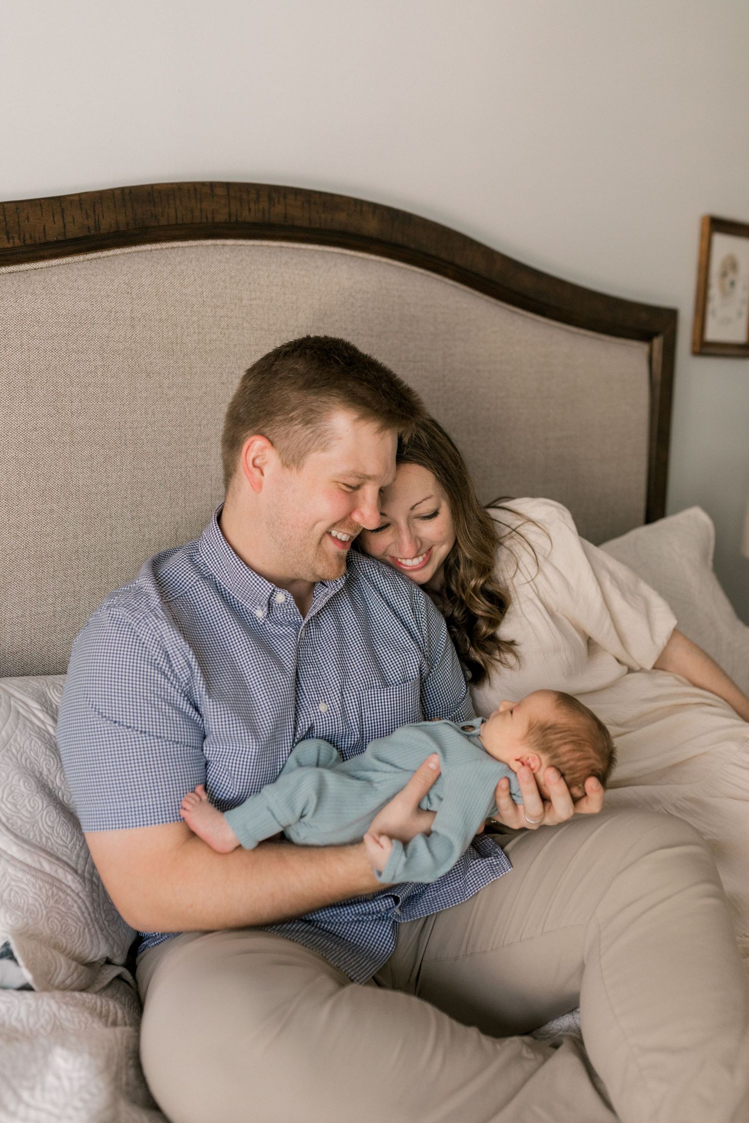 Parents tenderly admiring their newborn baby while resting on bed.