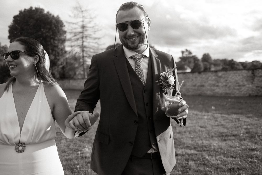 Black and white portrait of stylish couple walking during outdoor wedding.
