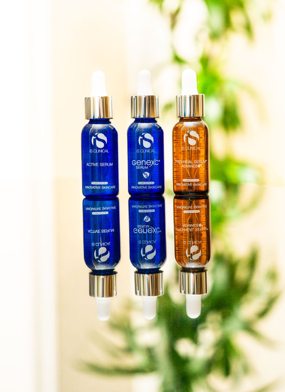 Reflection shot of blue and amber glass serum bottles against natural background.