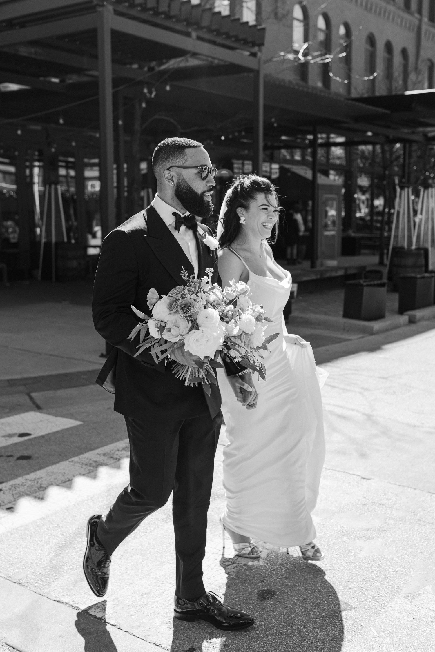 Black and white portrait of couple walking together on city sidewalk.